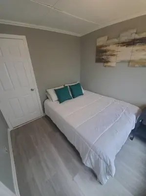 a bedroom with a white bed with two blue pillows at Beachy Bay Breeze Bungalow 2BR with parking and close to many amenities. in West Haven