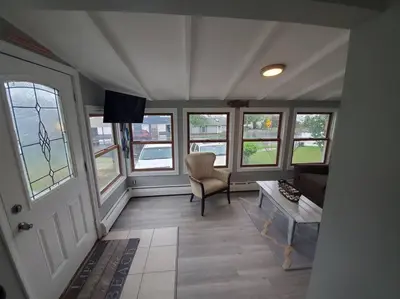 a living room with a couch and a table and windows at Beachy Bay Breeze Bungalow 2BR with parking and close to many amenities. in West Haven