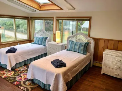 two beds in a room with windows at Direct Waterfront 4 Bedroom Beach House With Stunning LI Sound Views & Private Beach in Guilford