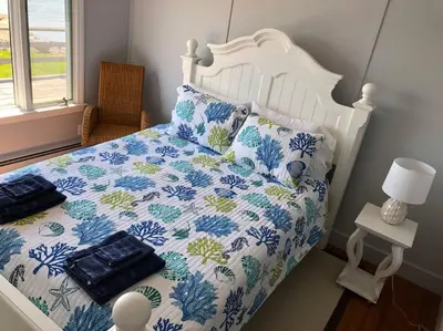 a bedroom with a bed with a blue and white bedspread at Direct Waterfront 4 Bedroom Beach House With Stunning LI Sound Views & Private Beach in Guilford