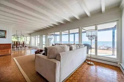 a living room with a couch and large windows at Direct Waterfront 4 Bedroom Beach House With Stunning LI Sound Views & Private Beach in Guilford