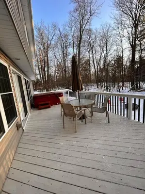 a patio with a table and chairs and an umbrella at Luxury 4 bedroom house in Pocono Mountains with Hottub in Golf Course Near Lake in Tobyhanna