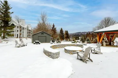 a snow covered yard with benches and a pond at All Season Mountain Retreat in Dover