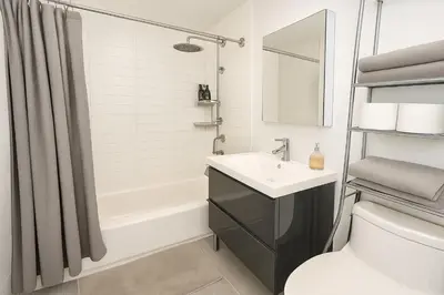 a bathroom with a sink and a tub and a toilet at Modern Studio with Private Bathroom and Kitchen in New York
