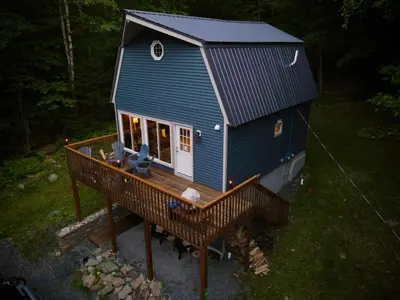 a blue house with a deck in the woods at Mandy's Mountain Chalet in Dover
