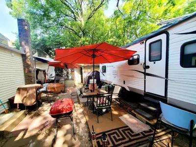 a patio with a table and an umbrella next to an rv at Black-white Rm By Yale U in New Haven