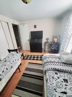 a living room with two beds and a flat screen tv at Black-white Rm By Yale U in New Haven