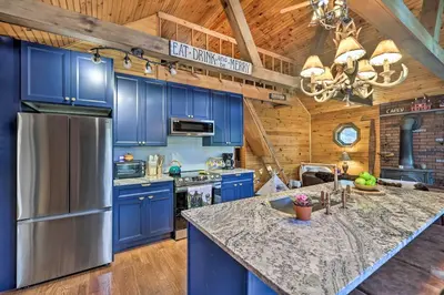 a kitchen with blue cabinets and a large kitchen island at Deck and Forest Views Secluded Cresco Cabin! in Cresco