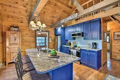 a kitchen with blue cabinets and a large island at Deck and Forest Views Secluded Cresco Cabin! in Cresco