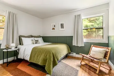 a green and white bedroom with a bed and a chair at Woodpecker House - Mountain retreat with hot tub - 10 min to skiing in Hunter & Windham in Jewett