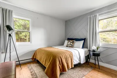 a bedroom with a bed and two windows at Woodpecker House - Mountain retreat with hot tub - 10 min to skiing in Hunter & Windham in Jewett