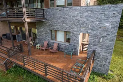 a large deck with chairs on a house at Stone Ledge in Margaretville