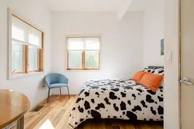 a bedroom with a cow print bed and a blue chair at Stone Ledge in Margaretville