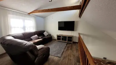 a living room with a leather couch and a flat screen tv at Pocono House in a private community 4 pools, Lake. in Tobyhanna