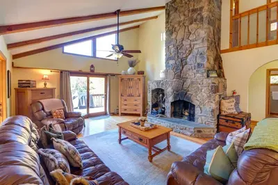 a living room with a couch and a stone fireplace at Birch Creek Lodge in Pine Hill