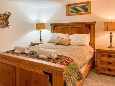 a bedroom with a wooden bed with two pillows on it at Birch Creek Lodge in Pine Hill