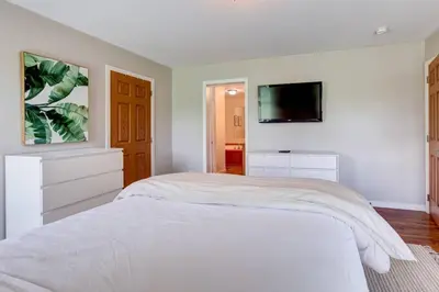 a white bedroom with a bed and a flat screen tv at Bluestone Hill House in Walton
