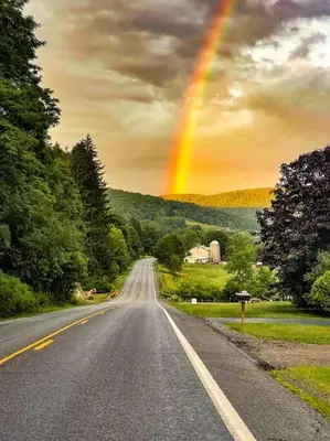 an empty road with a rainbow in the sky at Mountain Brook Cabin in Bovina Center