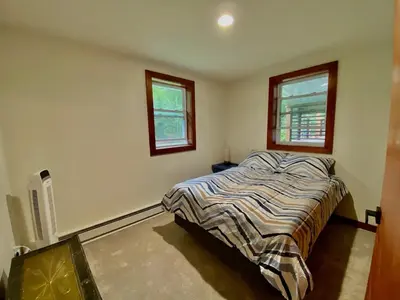 a bedroom with a bed and two windows at Hunter Mountain Sanctuary in Hunter