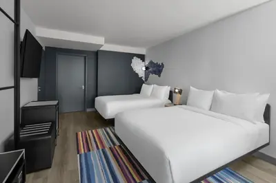 a hotel room with two beds and a flat screen tv at Aloft New York Chelsea in New York
