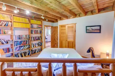 a bedroom with a bed in a room with bookshelves at Rustic Roost Cabin in Vega
