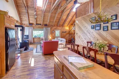 a kitchen and living room with wooden walls and a dining room at Rustic Roost Cabin in Vega