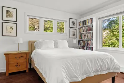 a white bedroom with a bed and two windows at Elenas by the Mill in East Meredith