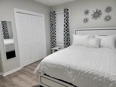 a white bedroom with a bed and a mirror at One room for rent shared bathroom and kitchen in Hartford