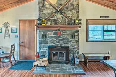 a stone fireplace in a living room with a table at Cozy Catskills Escape, 3 Mi to Plattekill Mtn in Roxbury