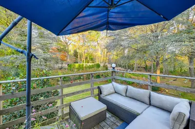 a patio with a couch and an umbrella at Cozy Dix Hills Apt with Deck about 7 Mi to Beach! in Dix Hills