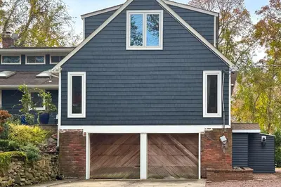 a house with a black roof and a garage at Cozy Dix Hills Apt with Deck about 7 Mi to Beach! in Dix Hills
