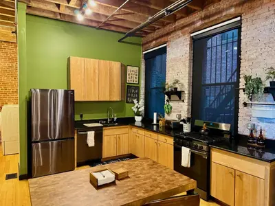 a kitchen with green walls and a stainless steel refrigerator at Brick City Loft in Newark