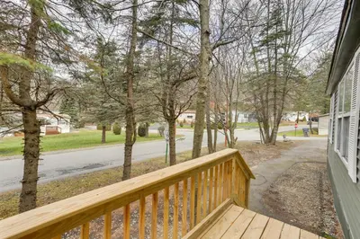 a porch with a wooden railing and trees on a street at Kayaks, Electric Bicycles Greentown Hideaway! in Greentown