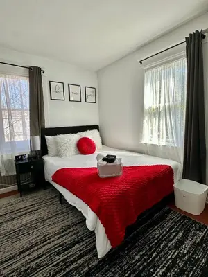a bedroom with a large bed with a red blanket at Modern Chic CoCo Chanel Inspired * Biz Friendly * Close To All in Hicksville
