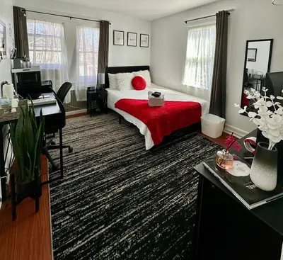 a bedroom with a bed with a red blanket and a desk at Modern Chic CoCo Chanel Inspired * Biz Friendly * Close To All in Hicksville