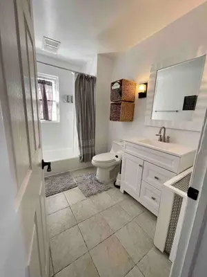 a white bathroom with a toilet and a sink at Modern Chic CoCo Chanel Inspired * Biz Friendly * Close To All in Hicksville
