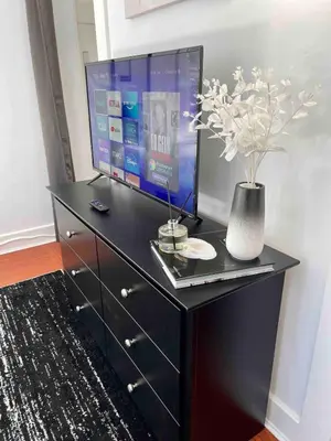 a black dresser with a tv on top of it at Modern Chic CoCo Chanel Inspired * Biz Friendly * Close To All in Hicksville