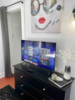 a tv on top of a dresser in a room at Modern Chic CoCo Chanel Inspired * Biz Friendly * Close To All in Hicksville