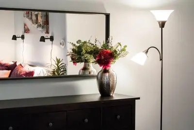 a vase with flowers on a dresser in front of a mirror at Gorgeous 1BR Wooster Sq. apt. - wshr/dryr, parking in New Haven