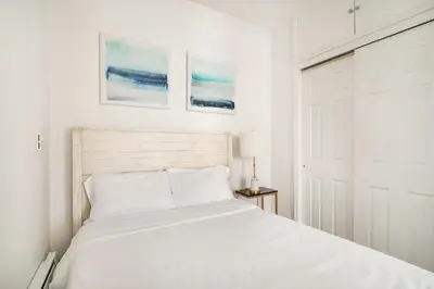 a white bedroom with a bed and two paintings on the wall at 69-2B Prime Lower East East BRAND NEW 1br Apt in New York
