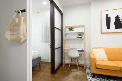 a living room with a mirror and a yellow couch at 69-2A PRIME Lower East Side 1br Apt Brand New in New York