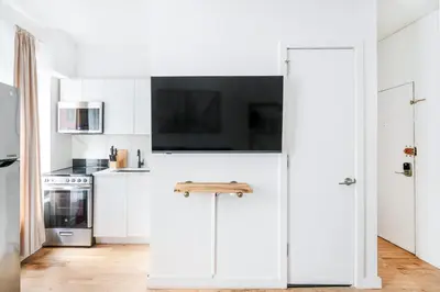 a white kitchen with white cabinets and a stove at 69-2C Brand New PRIME Lower East Side 1br Apt in New York