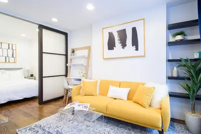 a living room with a yellow couch and a bed at 69-4A Quality NEW Prime Lower East East 1br Apt in New York