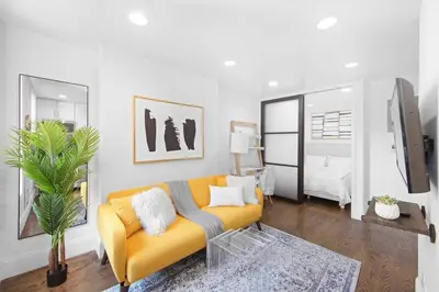 a living room with a yellow couch and a bedroom at 69-4B Modern Lower East Side 1BR PRIME LOCATION in New York