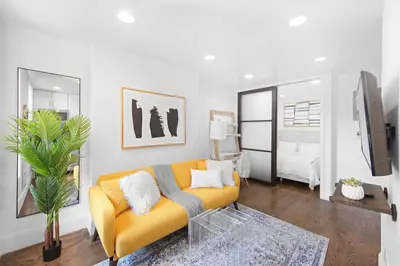 a living room with a yellow couch and a bedroom at 69-4B Modern Lower East Side 1BR PRIME LOCATION in New York