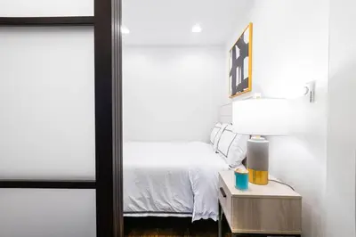 a bedroom with a bed and a table with a lamp at 69-4C PRIME Lower East Side 1br Apt Brand New in New York