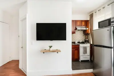 a kitchen with a white wall with a tv on it at 69-4D Trendy Lower East Side 1B BRAND NEW in New York