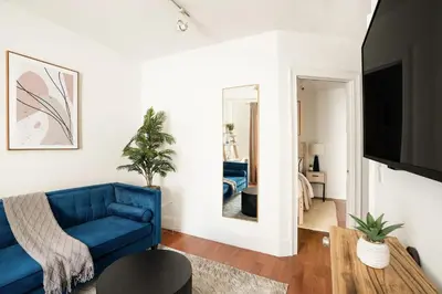a living room with a blue couch and a mirror at 69-4D Trendy Lower East Side 1B BRAND NEW in New York