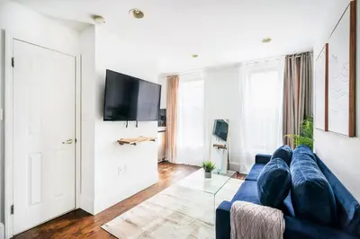 a living room with a blue couch and a tv at 69-5B I Stylish Lower East Side 1BR Apt BRAND NEW in New York