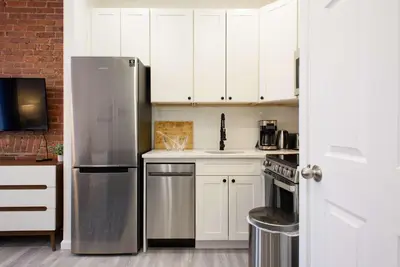 a kitchen with white cabinets and a stainless steel refrigerator at 240-11 NEW STUDIO Prime Upper East W&D in New York
